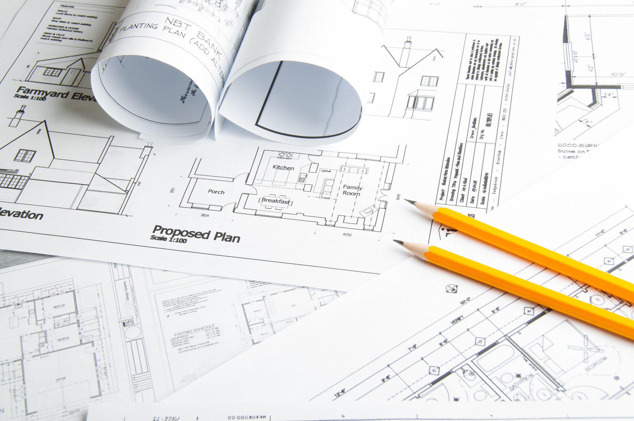 Construction planning drawings on the table and two yellow pencils